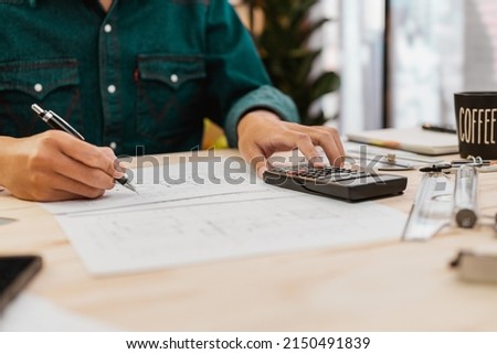 Close up Architect or Engineer pressing on calculator for calculating value estimating for safety with the drawing construction building.