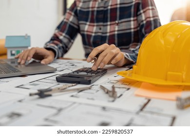 Close up Architect or Engineer using on calculator for calculating value estimating for safety with the drawing construction building