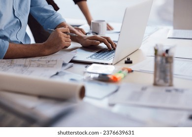 Close up of a architect sketching design and using a laptop in a modern office - Powered by Shutterstock