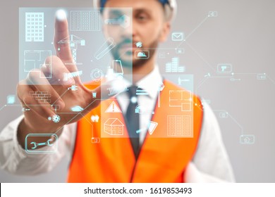 Close Up Of Architect Wearing Reflective Vest And Helmet. Selective Focus Of Digital Tactile Charts Screen, Man Touching Virtual Icon On Projection. Concept Of Digitalization, Construction.