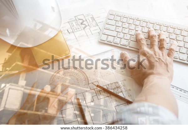 Close up
of Architect working on blueprint with computer at workplace.Double
exposure of construction
site.