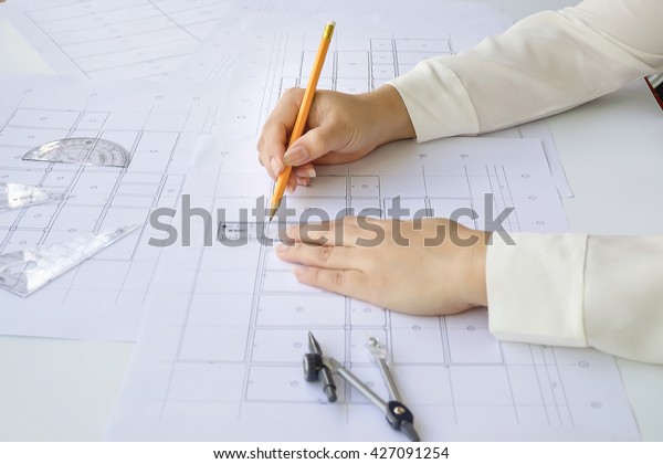 Close up Architect working on blueprint. Architects\
workplace - architectural  working of Architect sketching a\
construction project on his plane project. Construction concept.\
Engineering tools