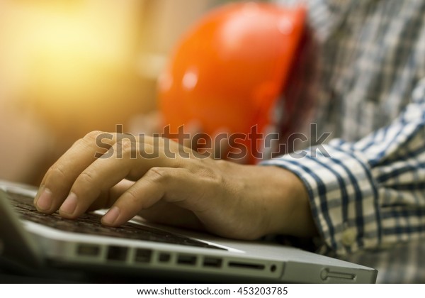 Close up\
of Architect working on blueprint with computer at workplace.Double\
exposure of construction\
site.