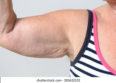 Close Up Arm Muscles And Underarm Of A Middle Aged Woman In Casual Sleeveless Shirt, Isolated On Gray Background.