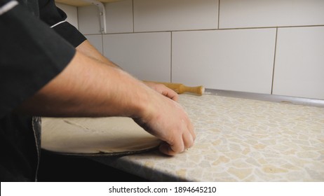 Close Up Arms Of Cook Putting Dough In The Metal Form For Pizza On A Wooden Surface At Cuisine. Male Hands Of Chef Preparing Pastry To Baking On A Table At Restaurant. Food Cooking Concept. Slow Mo