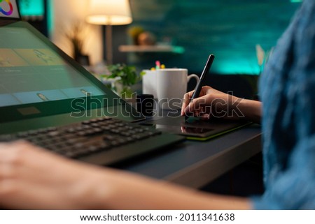 Close up of artistic hand using digital tablet and stylus while retouching image design at professional studio office desk. Woman doing editing work on editor software with modern equipment
