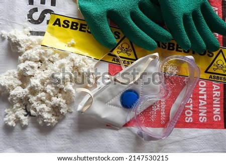 Close up asbestos, fibers, mask, filter, gloves and goggles. Bag in background. Barrier tape, warning forbidden acces, hazard. Asbestos removal. Asbestosis, lungcancer, mesothelioma. Protection, serie