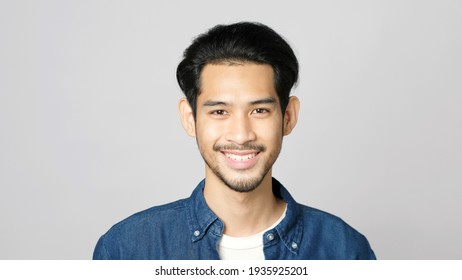 Close Up Of Asia Man Smiling And Looking At Camera While Standing Over Isolated Grey Background 