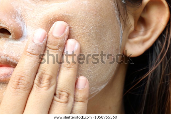 Close up Asia woman cheek. Woman\
washing face (have wide pores) with white foam by her\
hand.