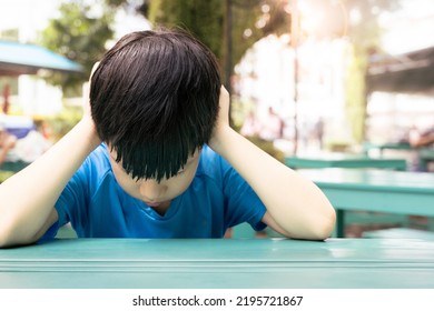 Close Up Of Asian Autistic Student Child Sit At Table At School Cover Ears With Hand And Close Eyes Due To Stress And Anxiety. Autism Stimming Behavior For World Autism Spectrum Awareness Day Concept