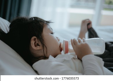 Close up of Asian baby girl drinking milk from bottle.