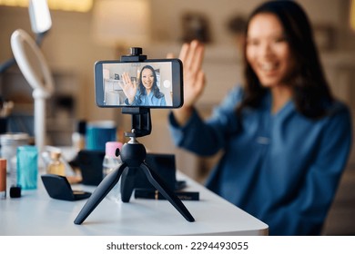 Close up of Asian beauty influencer greeting her followers while recording makeup vlog. - Powered by Shutterstock