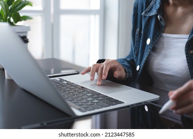 Close up of asian business woman surfing the internet, searching information on laptop computer and digital tablet pc, online working from home office, telecommuting. Freelancer working on computer 