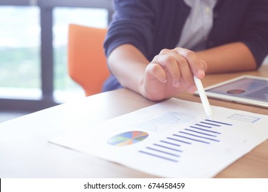 close up asian businesswoman hand holing stylus pen and pointing on kpi statistic stock graph profit paper for explaining data information,business financial concept