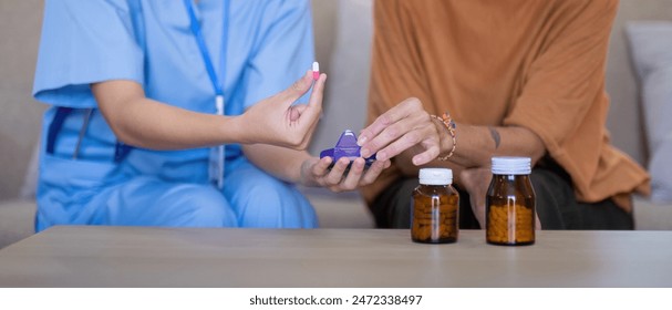 Close up of Asian caregiver demonstrating medication to elderly woman at home. Concept of elderly care and medication management - Powered by Shutterstock