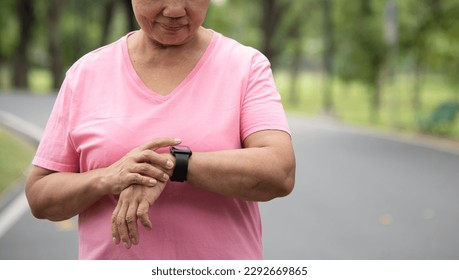 Close up Asian Chinese senior woman checking her heartbeat with smart watch at nature park. Mature Adult female checking pulse after jogging. Fitness tracker - Powered by Shutterstock