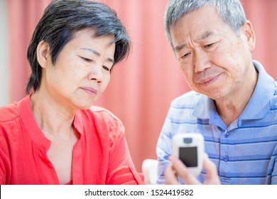 close up of asian elder couple use blood glucose meter and worry about it - Prevention diabetes concept