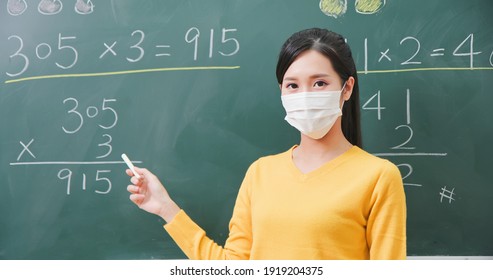 Close Up Of Asian Elementary School Female Teacher Wearing Face Mask Teach Math Online Through Webcam In Classroom