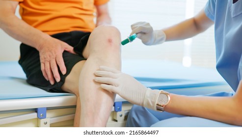 Close Up Of Asian Female Doctor Wearing Face Mask Is Examiniting Senior Elder Man Patient Joint With Percussion Hammer To Check His Knee Jerk Reflex