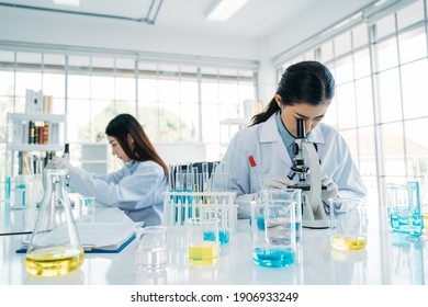 Close Up Of Asian Female Scientist Research Team In Protective Gear Using Microscope In The Laboratory To Develop Antivirus Vaccine 