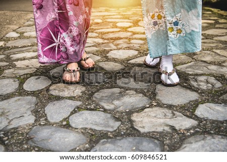 Close up of asian girlfriends wearing kimono and geta traditional Japanese footwear walking to traditional ceremony or street shopping with sunlight in japan. vintage style