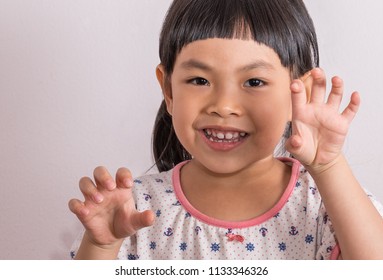 Close up Asian little girl in funny moment, playing and acting as monster or tiger or dragon by showing claws.