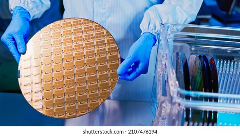 close up of asian male technician in sterile coverall holds wafer with gloves that reflects many different colors and check it at semiconductor manufacturing plant