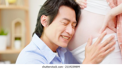 Close Up Of Asian Man Is Listening Pregnant Wife Belly And Expecting Their Baby Coming At Home