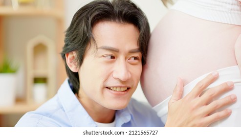 Close Up Of Asian Man Is Listening Pregnant Wife Belly And Expecting Their Baby Coming At Home