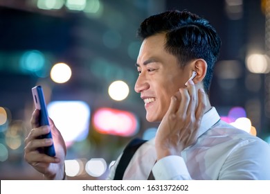 close up of asian man speak to phone by wearing wireless earbuds while walking on the street