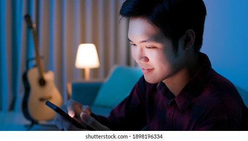 Close Up Of Asian Man Use Smart Phone And Feel Happy On Sofa At Home