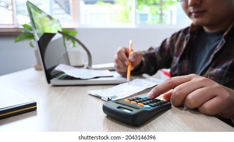 Close Up Of Asian Man Using Calculator And Managing Household Finances At Home.