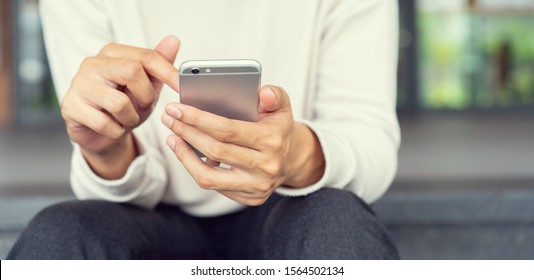 Close up asian man using smart phone mobile device for play or shopping online or check time and date , teenager with technology and social distance concept