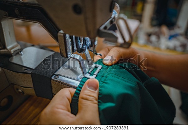 Close up Asian man working at the bartack machine,\
industrial series. Close up Asian woman working at the stitching\
machine, industrial series. Textile cloth factory working process\
tailoring workers 