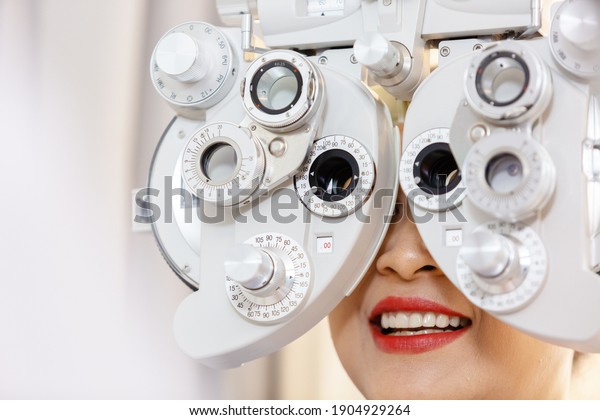 Close up asian\
middle age woman eye exam with diagnostic ophthalmology in optical\
clinic. professional ophthalmic checking vision of patient.\
phoropter machine, ophthalmology\
concept.