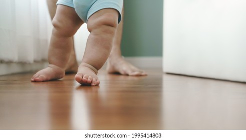 Close Up Asian Mother Holding Her Little Baby Learning To Walk On Wooden Floor At Home. Cute Toddler Enjoying The First Steps With Mom.