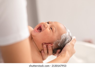 Close up asian newborn baby bathing in bathtub. mother bathing her son in warm water. Happy adorable newborn infant smile in tub relax and comfortable good moment with mom. Newborn baby care concept