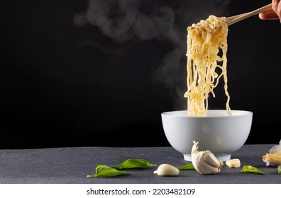 Close Up Of Asian Noodles Held In Chopsticks By Caucasian Man On Black Background. Asian Tasty Home Cooked Food And Healthy Eating.