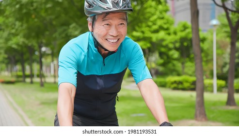 Close Up Of Asian Old Man Wearing Helmet Is Cycling A Bicycle In The Park - Enjoying Sport Or Hobby Living Healthy