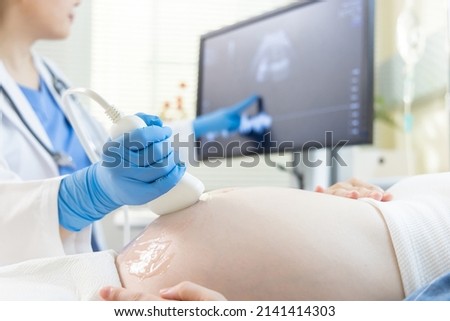 close up of asian pregnant woman lying in hospital ward has uterus utltrasonographic diagnosis - female doctor scans her uterus and shows on screen