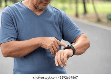 Close up Asian senior man checking his heartbeat with smart watch at nature park. Mature Adult male checking pulse after jogging. Fitness tracker - Powered by Shutterstock