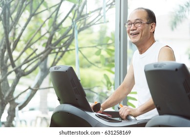 Close Up Asian Senior Man Exercising On Treadmill Machine With Copy Space. Relaxing And Smiling.