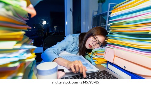 close up of asian tired young businesswoman is lying on desk while working overtime with laptop and documents in office - Shutterstock ID 2145798785