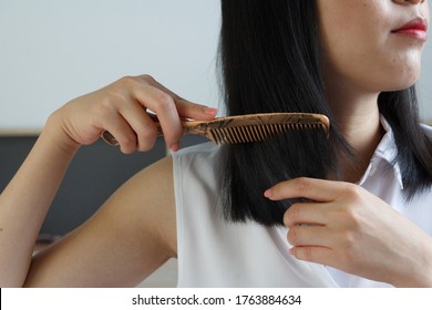 Close up of Asian woman combing hair.