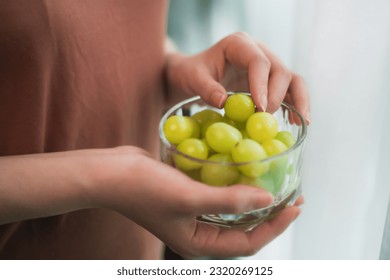 close up asian woman eating fresh Green grapes keep for health at home.
Organic Fresh Fruits for a Healthy.
Diet and healthy food concept. - Powered by Shutterstock