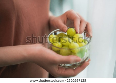 close up asian woman eating fresh Green grapes keep for health at home.
Organic Fresh Fruits for a Healthy.
Diet and healthy food concept.