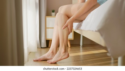 close up of asian woman hand touch massage her calf on floor in bedroom at home - she has leg cramp muscle pain
