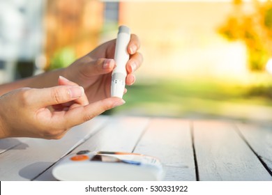Close up of asian woman hands using lancet on finger to check blood sugar level by Glucose meter, Healthcare Medical and Check up, 