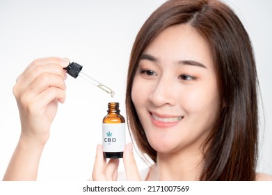 Close Up Asian Woman Looks At A Bottle Of CBD Oil. Sleep Supplement. Medical Marijuana. Vitamins And Supplements Healthy Alternatives.
