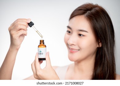 Close Up Asian Woman Looks At A Bottle Of CBD Oil. Sleep Supplement. Medical Marijuana. Vitamins And Supplements Healthy Alternatives.
